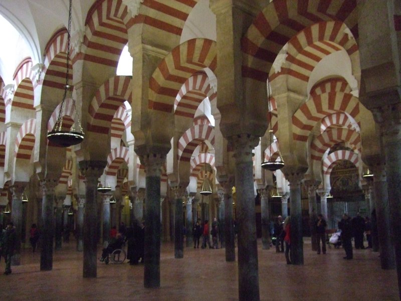The hypostyle prayer hall of the Mezquita-Catedral de Córdoba — double-tiered red-and-white horseshoe arches resting on a forest of jasper and marble columns, UNESCO World Heritage Site since 1984